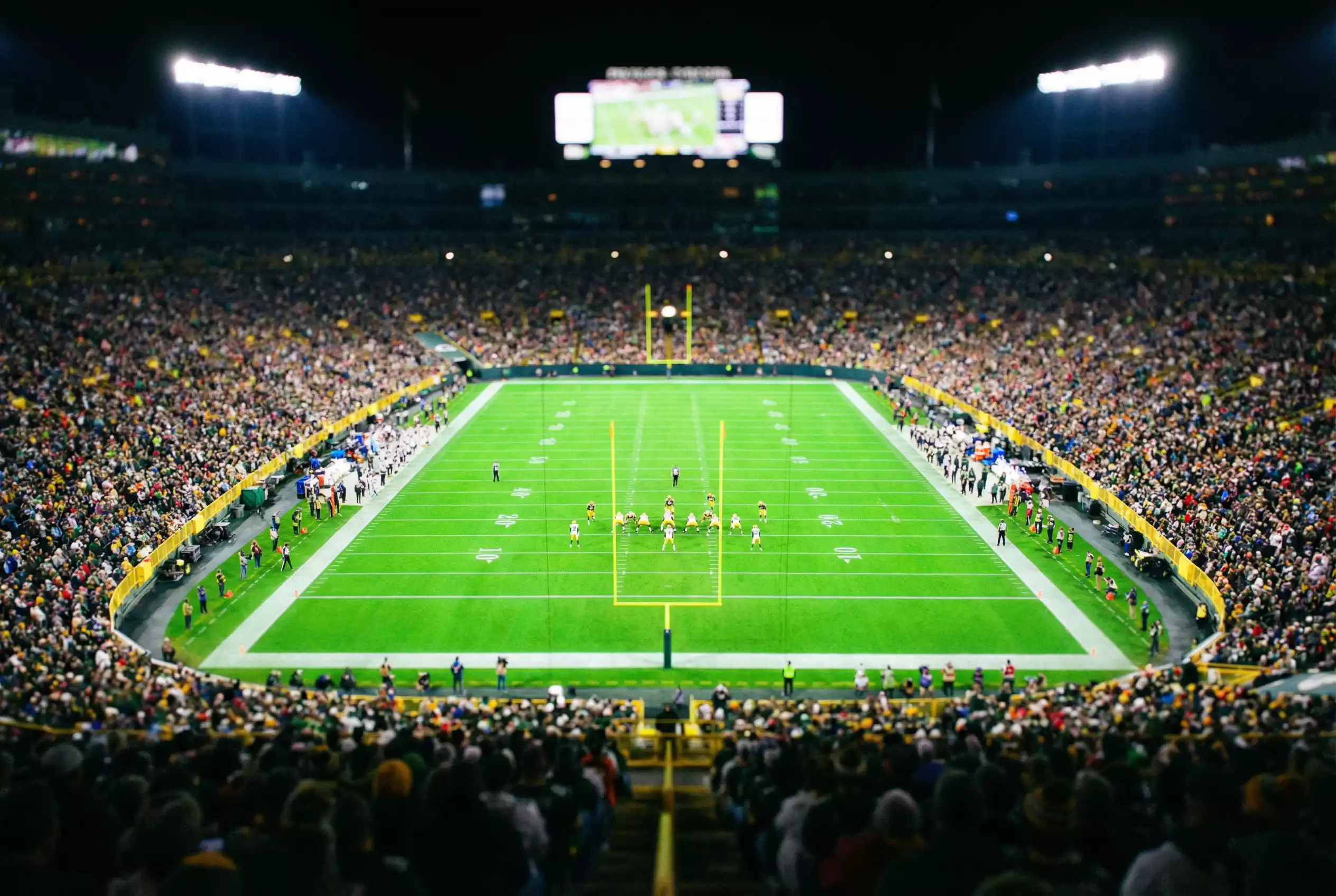Espectadores viendo un partido de fútbol americano de la NFL en un estadio lleno de noche