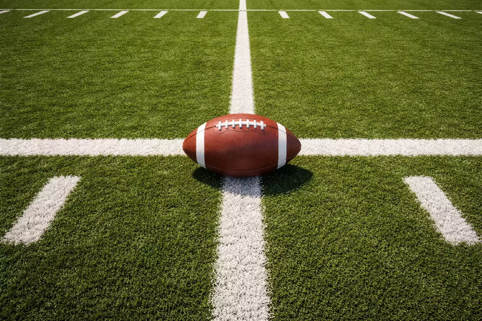 Jugadores de fútbol americano en formación sobre campo de césped con líneas de yardas